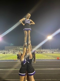 Hailey doing an extension with bases and backstop holding her up, in the air.