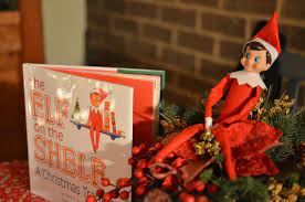 Elf on the shelf chilling out in his hiding spot. besides the famous book that started the tradition. 