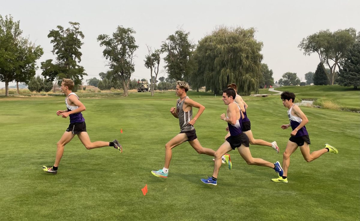 Rocky XC runners (from left to right) Hyrum Tuft, Parker Goggins, Cody Lucas, and Tommy Kurtz surround Canyon Ridge runner at the start of the Jerome Open Invite