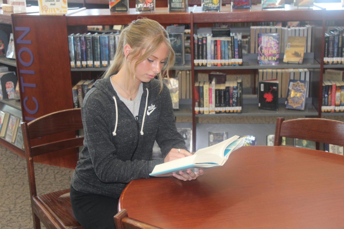 Kayla Newburn reading a book in Rocky Mountain Highschool's library 