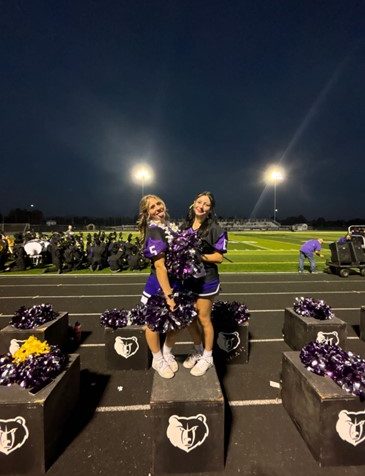 A picture of Morgan Carlson, on the left, who is a senior and cheers on the Rocky Mountain Varsity cheer team with Chelsea Oxsen on the right. In this picture they are at the Rocky homecoming game. 