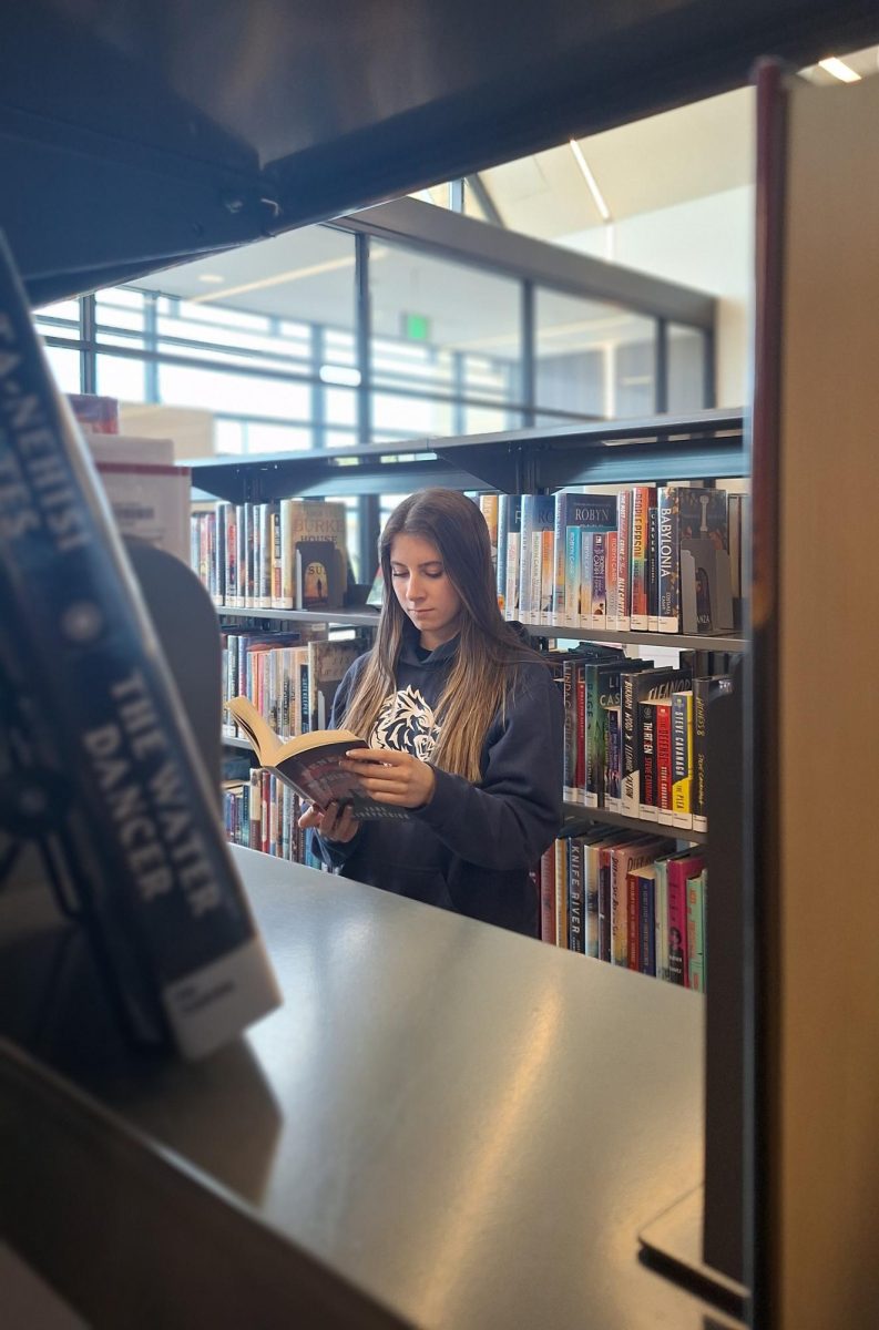 Anna Walsh, a senior here at rocky, reads intently among the books of the Orchard Park Library